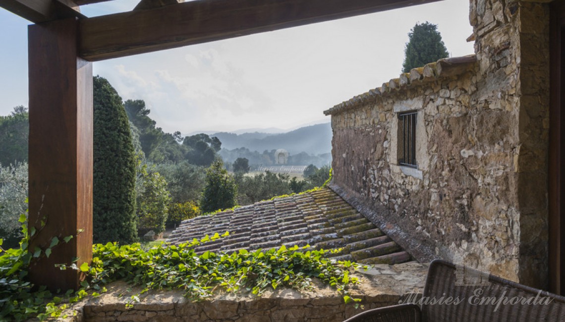 Vista desde el porche de parte de la masía y de los campos que la rodean 