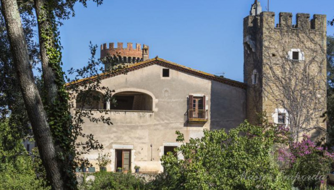 Vista desde el lateral de la masía donde se aprecia el detalle curioso y singular de la torre redonda en segundo término de la imagen y el de la torre cuadrada en primer término. 