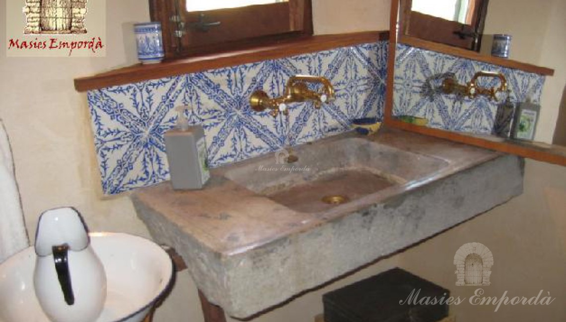 Baño de planta con pica de piedra y azulejos de cenefas azules en fondo blanco