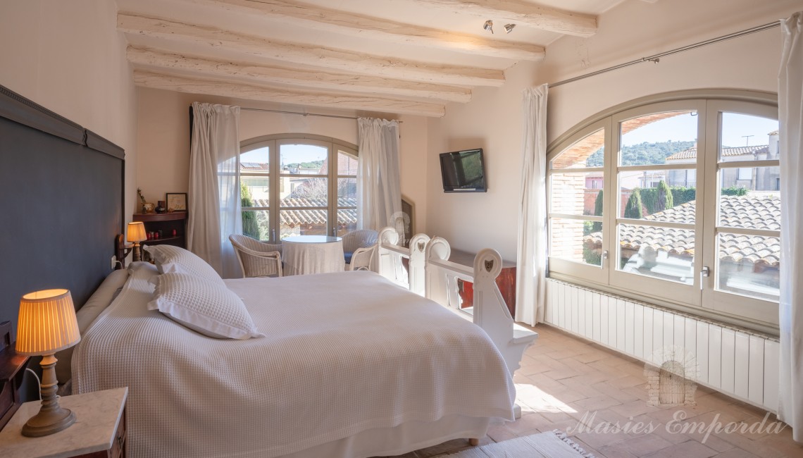 Habitación principal de la casa con salida a la terraza y vistas al jardín y piscina