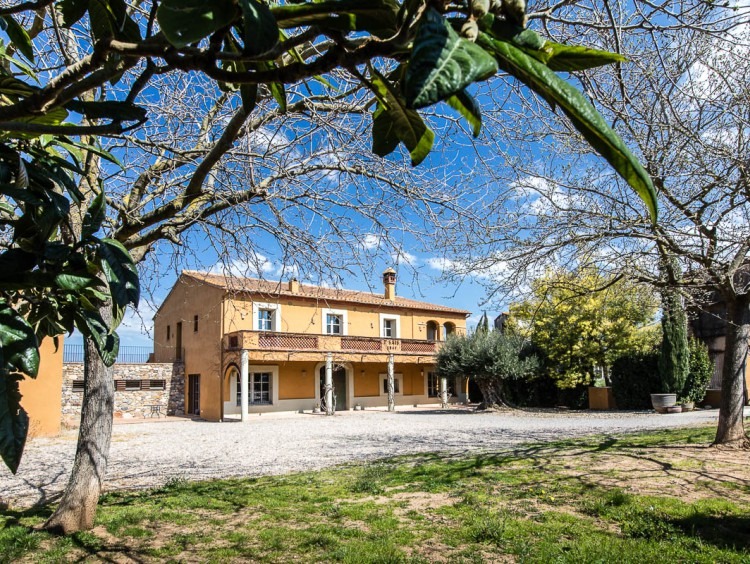 Vista de la fachada de la masía y el jardín  